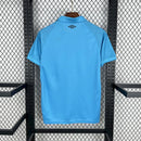 Close nos detalhes da camisa Santos 25/26 Umbro azul, mostrando o escudo bordado e a gola personalizada.