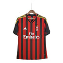 Vista frontal da camisa retrô AC Milan 2013/14, modelo home com listras vermelhas e pretas, escudo centralizado e gola polo clássica.

